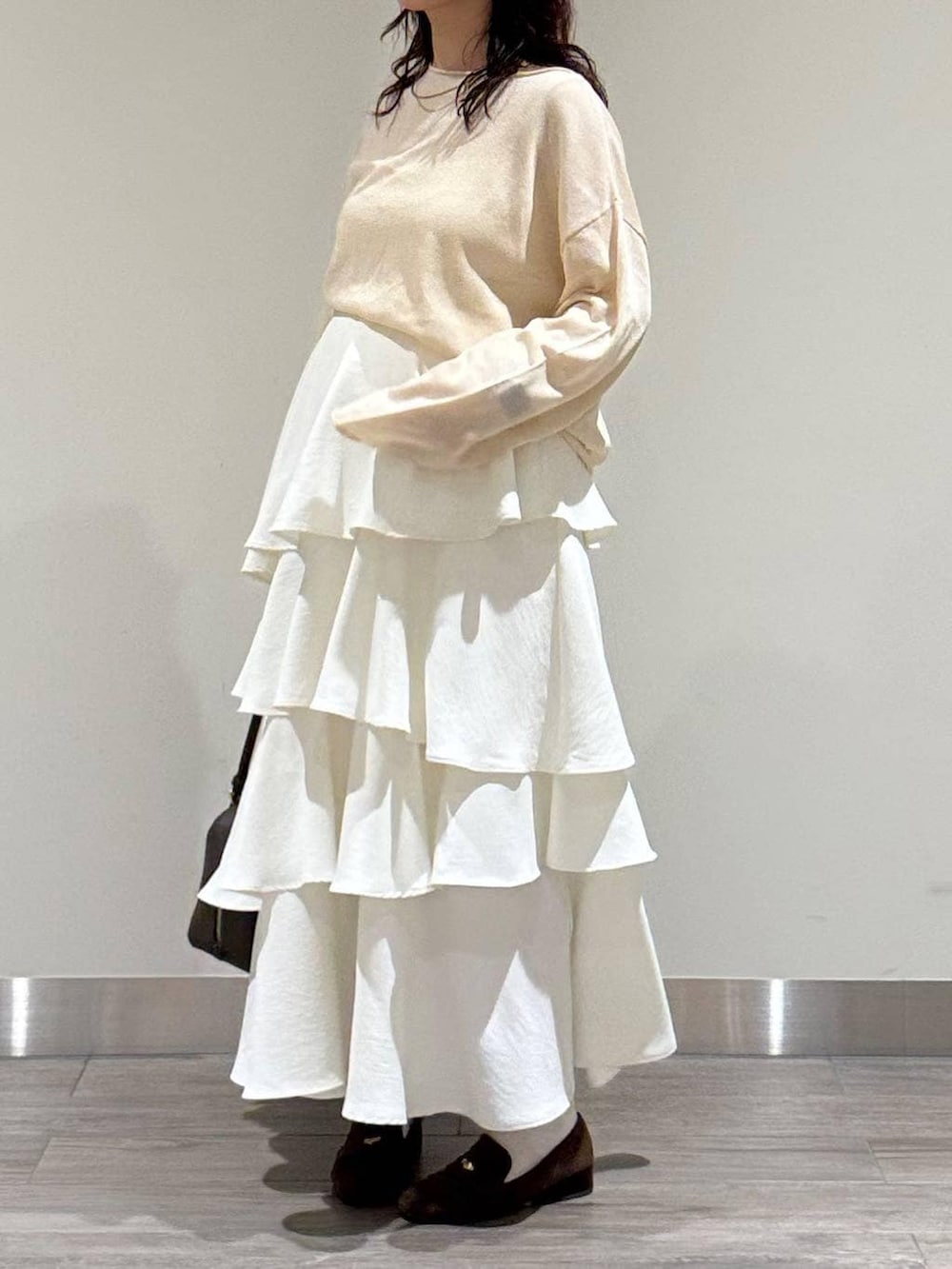 ホワイト系のニット/セーター、ブラウン系のハンドバッグ、ブラウン系のローファーを着用したレディースの春コーディネートの5枚目の写真