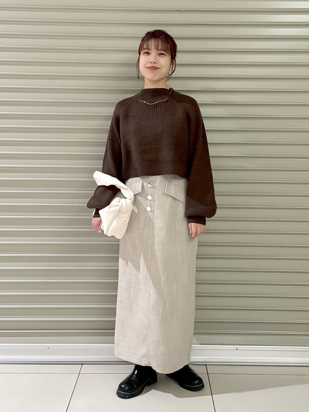 ブラック系のブーツ、ホワイト系のハンドバッグ、ホワイト系のスカートを着用したレディースの冬コーディネートの4枚目の写真