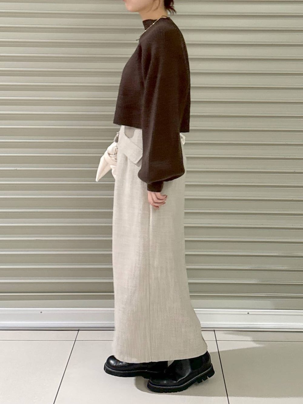 ブラック系のブーツ、ホワイト系のハンドバッグ、ホワイト系のスカートを着用したレディースの冬コーディネートの2枚目の写真