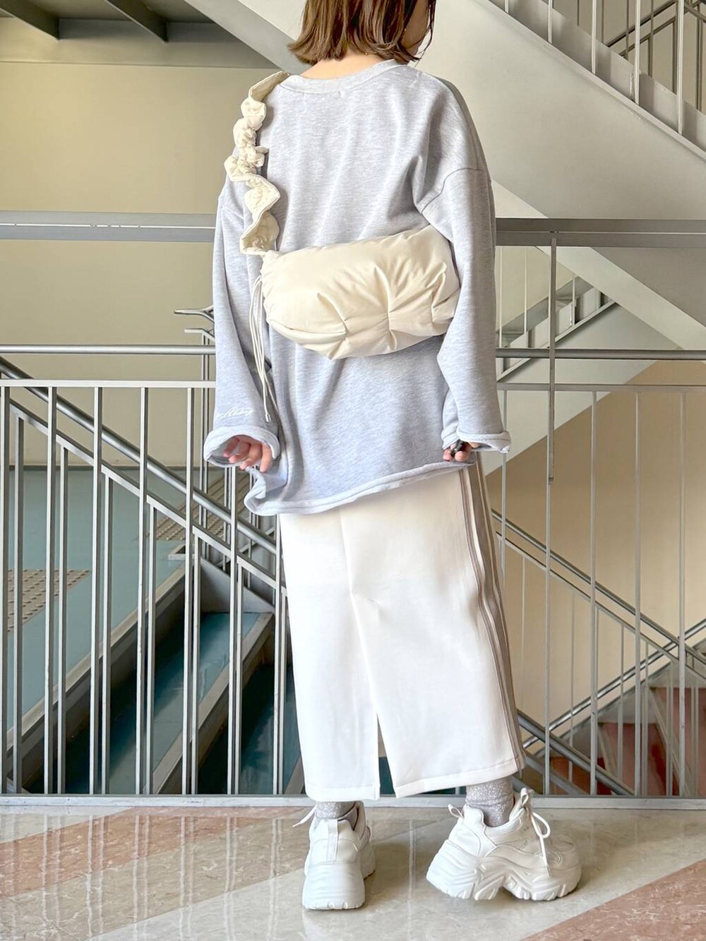 ホワイト系のスカート、グレー系のスウェット、ホワイト系のハンドバッグを着用したレディースの冬コーディネートの3枚目の写真