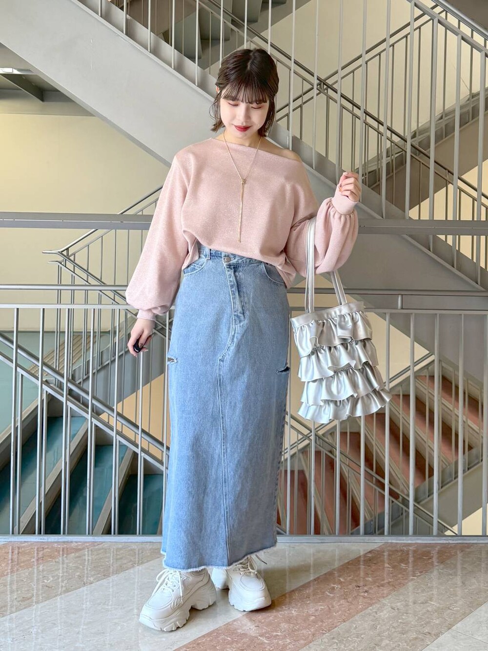 シルバー系のトートバッグ、ホワイト系のスニーカー、ブルー系のスカートを着用したレディースの冬コーディネートの4枚目の写真