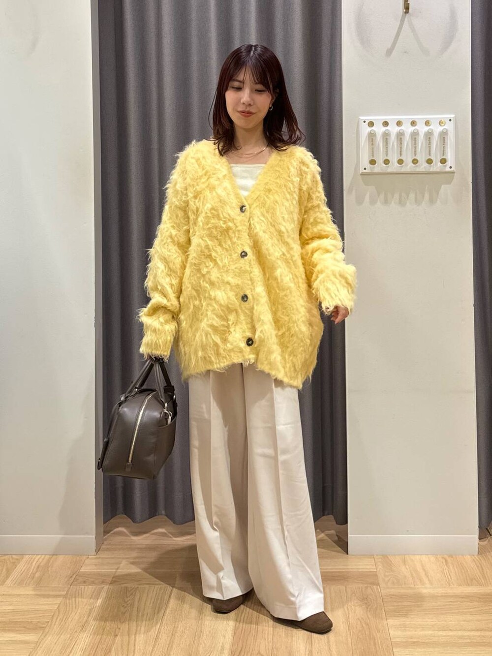 ブラウン系のハンドバッグ、イエロー系のカーディガン/ボレロ、ブラウン系のローファーを着用したレディースの秋コーディネートの6枚目の写真