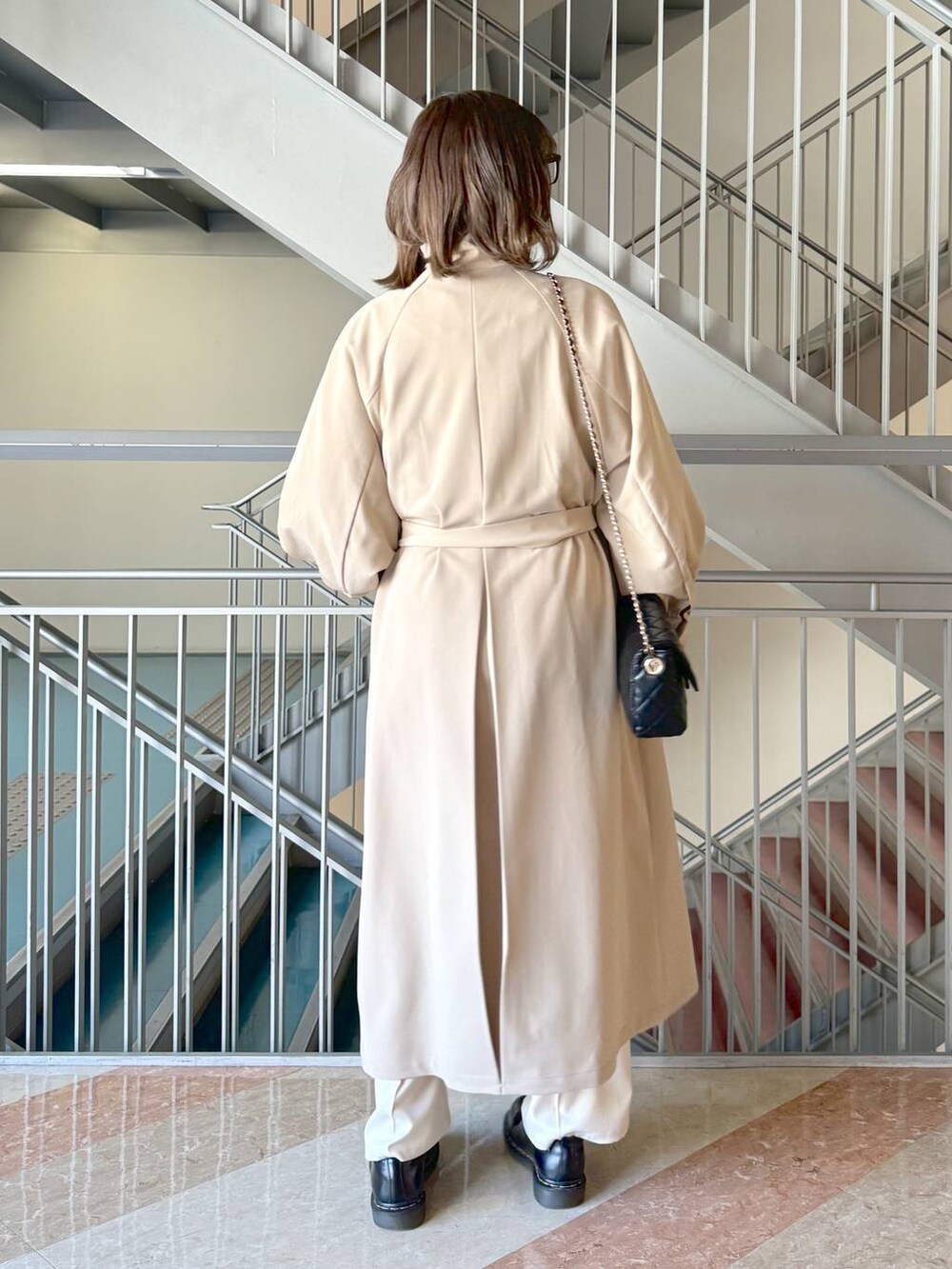 グレー系のニット/セーター、ブラック系のショルダーバッグ、ホワイト系のその他パンツを着用したレディースの春コーディネートの4枚目の写真