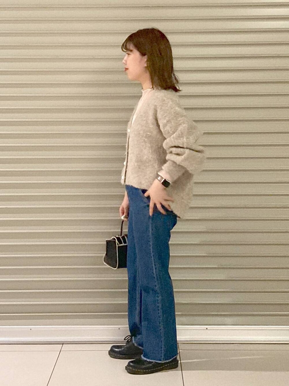 ブルー系のデニムパンツ、ブラック系のハンドバッグ、ブラウン系のカーディガン/ボレロを着用したレディースの秋コーディネートの3枚目の写真