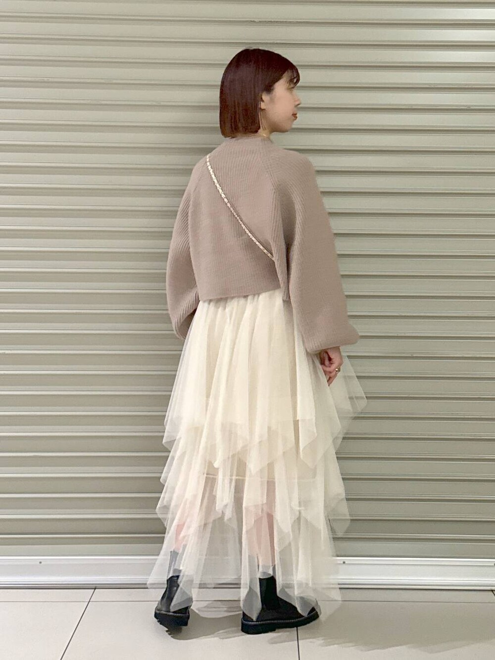 ホワイト系のノーカラーコート、ブラック系のブーツ、ピンク系のハンドバッグを着用したレディースの冬コーディネートの6枚目の写真