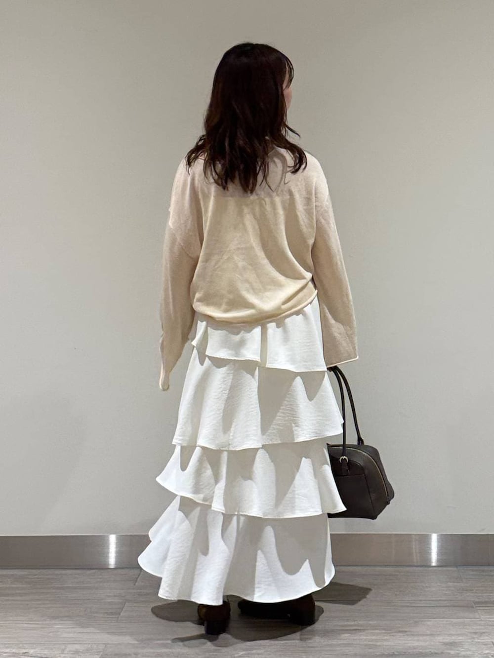 ホワイト系のニット/セーター、ブラウン系のハンドバッグ、ブラウン系のローファーを着用したレディースの春コーディネートの4枚目の写真