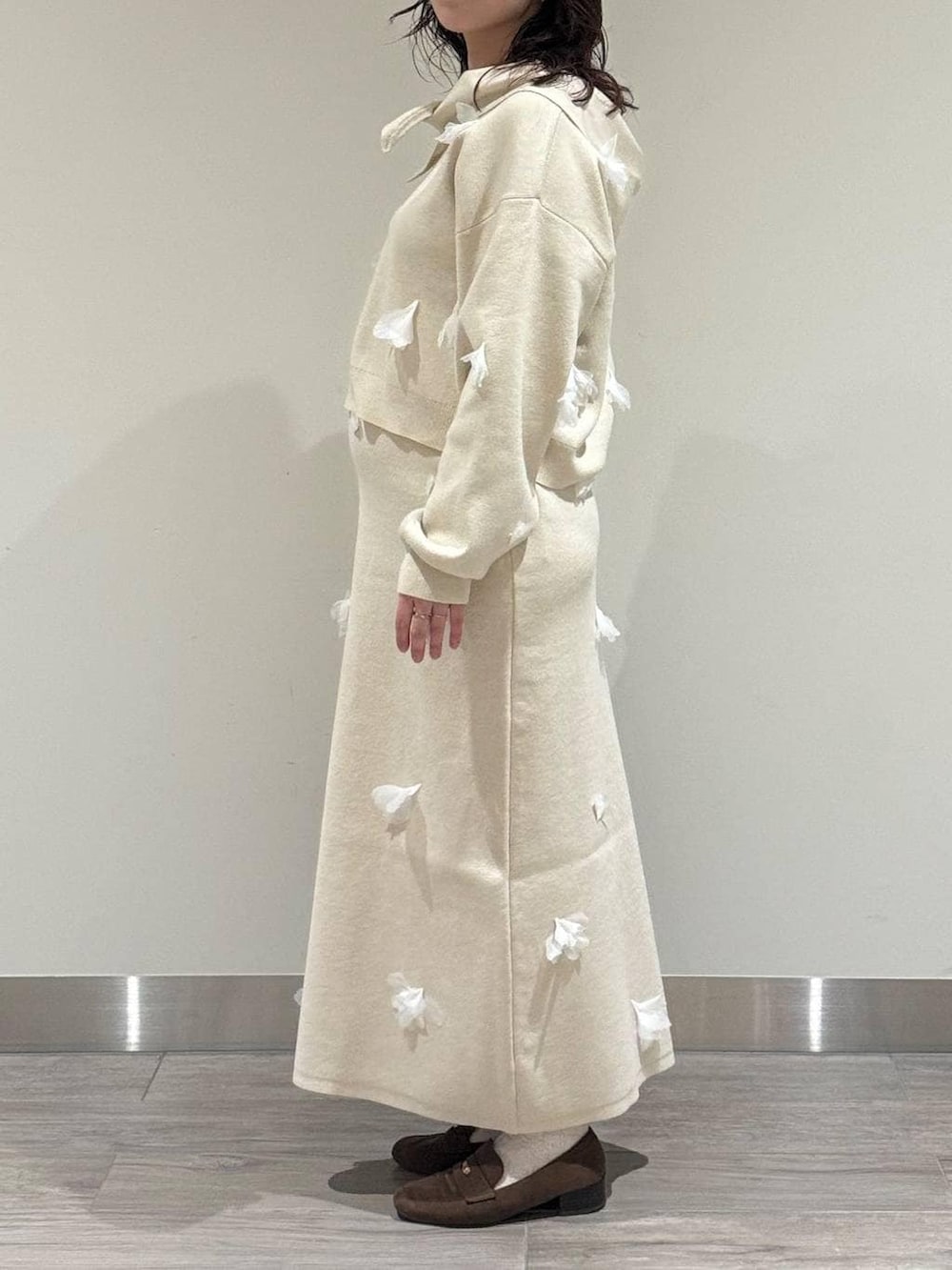 ブラウン系のハンドバッグ、ブラウン系のローファー、ホワイト系のニット/セーターを着用したレディースの冬コーディネートの3枚目の写真