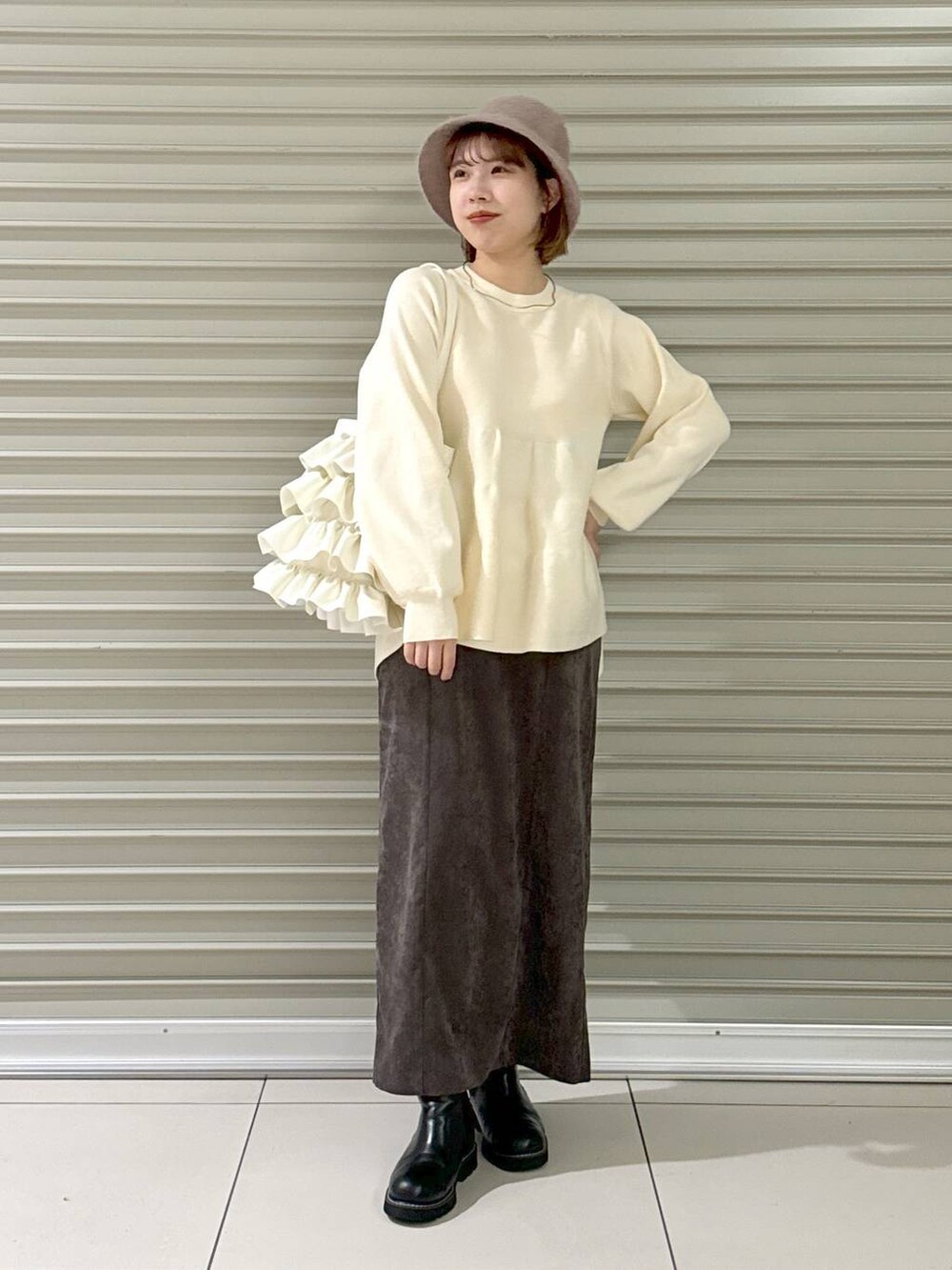 ブラウン系のスカート、ブラック系のブーツ、ホワイト系のトートバッグを着用したレディースの冬コーディネートの4枚目の写真