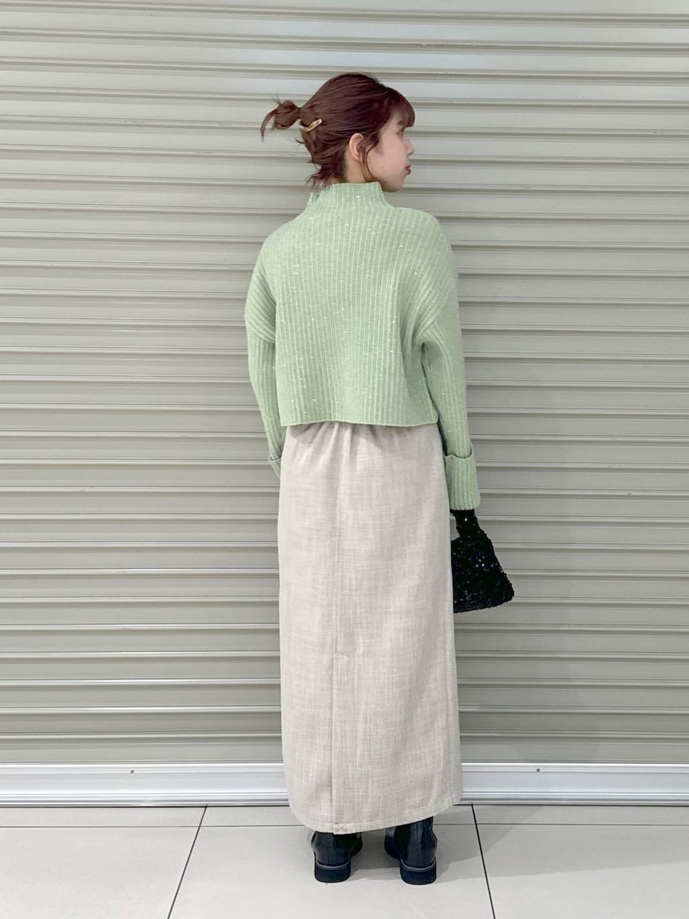 ブラック系のブーツ、ホワイト系のスカート、ブラック系のハンドバッグを着用したレディースの冬コーディネートの3枚目の写真