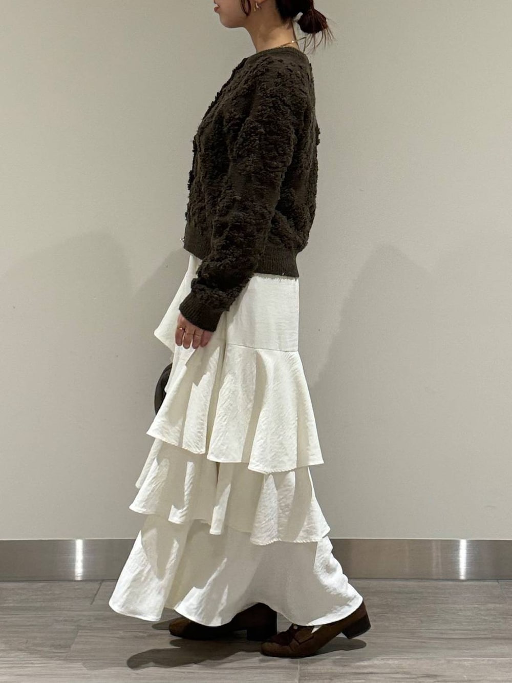 ブラウン系のハンドバッグ、ブラウン系のカーディガン/ボレロ、ホワイト系のスカートを着用したレディースの秋コーディネートの4枚目の写真
