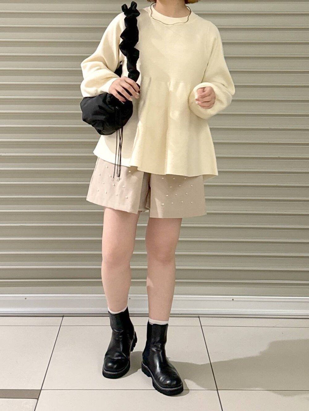 ブラック系のハンドバッグ、ブラック系のブーツ、ベージュ系のその他パンツを着用したレディースの冬コーディネートの2枚目の写真