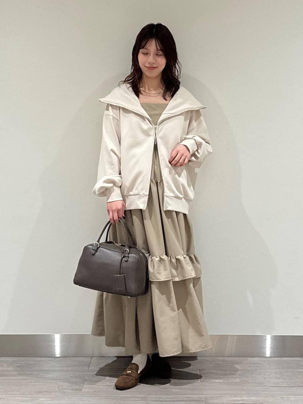 ホワイト系のキャミソール、ブラウン系のハンドバッグ、ブラウン系のローファーを着用したレディースの冬コーディネートの2枚目の写真