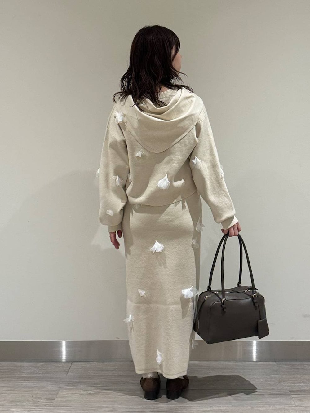 ブラウン系のハンドバッグ、ブラウン系のローファー、ホワイト系のニット/セーターを着用したレディースの冬コーディネートの4枚目の写真