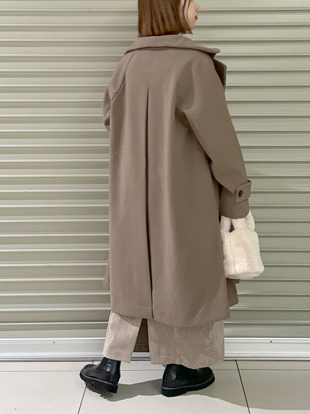 ブラウン系のスカート、ブラウン系のチェスターコート、ホワイト系のキャミソールを着用したレディースの冬コーディネートの5枚目の写真