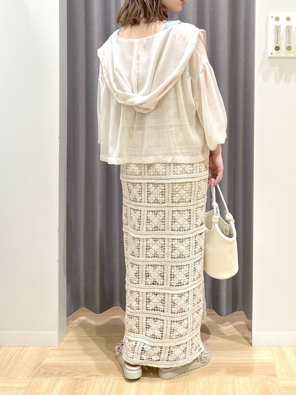 グレー系のサンダル、ホワイト系のハンドバッグ、ブルー系のタンクトップを着用したレディースの夏コーディネートの3枚目の写真