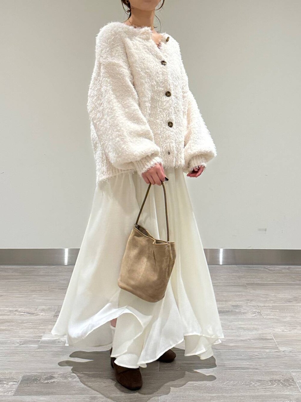 ホワイト系のカーディガン/ボレロ、ホワイト系のスカート、ブラウン系のローファーを着用したレディースの秋コーディネートの2枚目の写真
