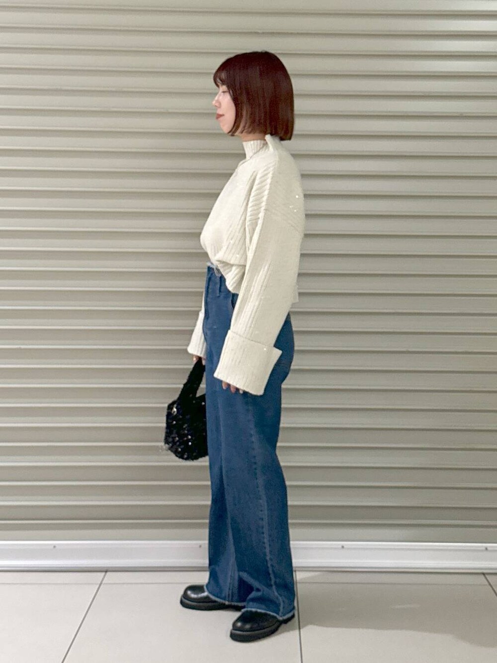 ブルー系のデニムパンツ、ブラック系のブーツ、ブラック系のハンドバッグを着用したレディースの秋コーディネートの4枚目の写真