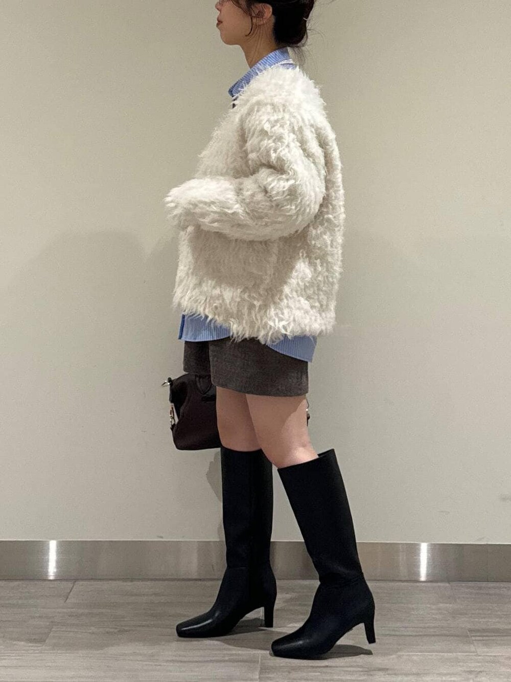 ブラウン系のボストンバッグ、ホワイト系のカーディガン/ボレロ、ブラウン系のその他パンツを着用したレディースの冬コーディネートの4枚目の写真