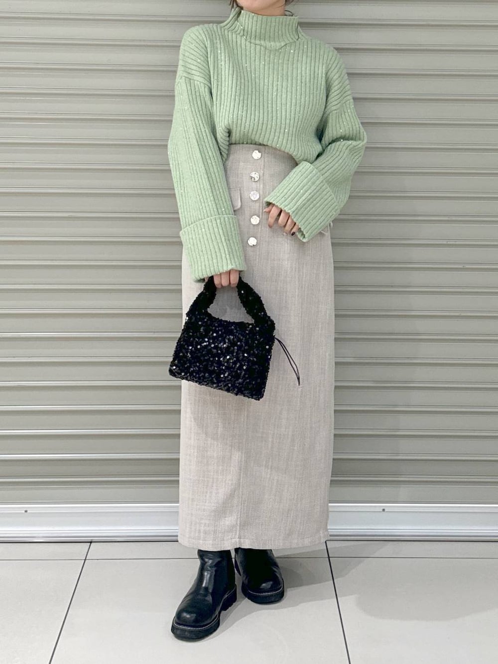 ブラック系のブーツ、ホワイト系のスカート、ブラック系のハンドバッグを着用したレディースの冬コーディネートの2枚目の写真