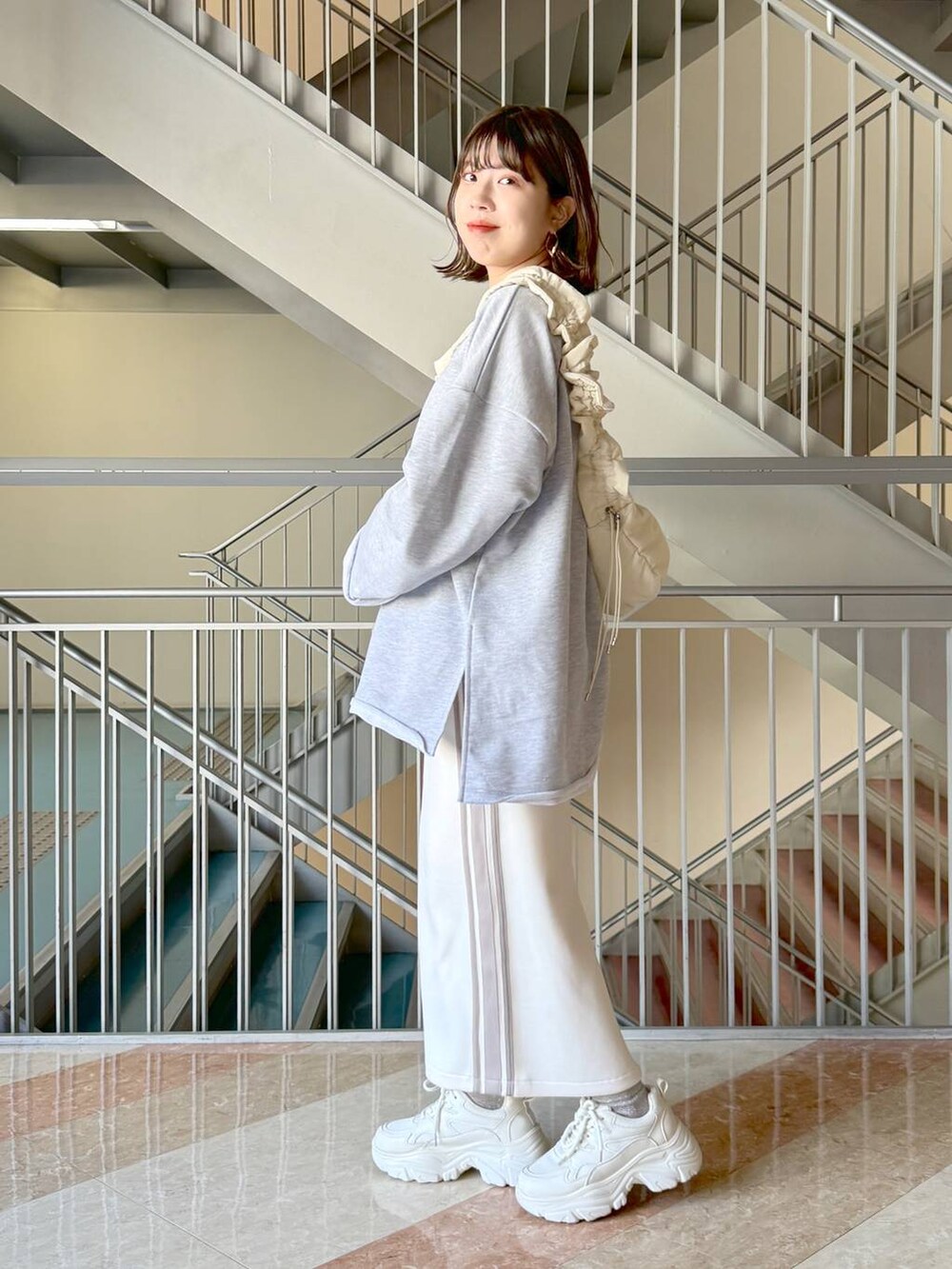 ホワイト系のスカート、グレー系のスウェット、ホワイト系のハンドバッグを着用したレディースの冬コーディネートの2枚目の写真