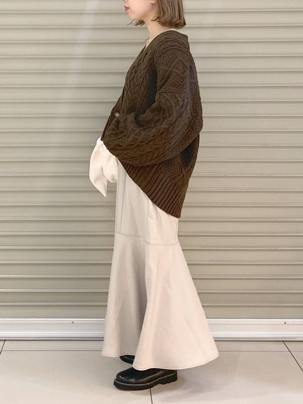 ベージュ系のキャミソール、ブラック系のブーツ、ベージュ系のスカートを着用したレディースの秋コーディネートの2枚目の写真