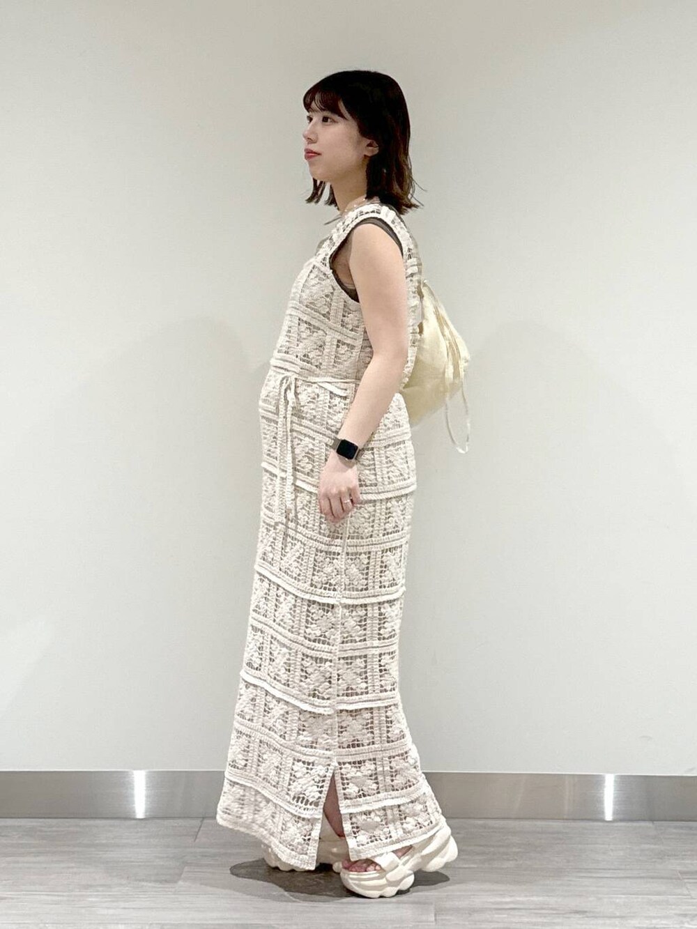 ホワイト系のワンピース、ブラウン系のニット/セーター、ホワイト系のサンダルを着用したレディースの春コーディネートの3枚目の写真