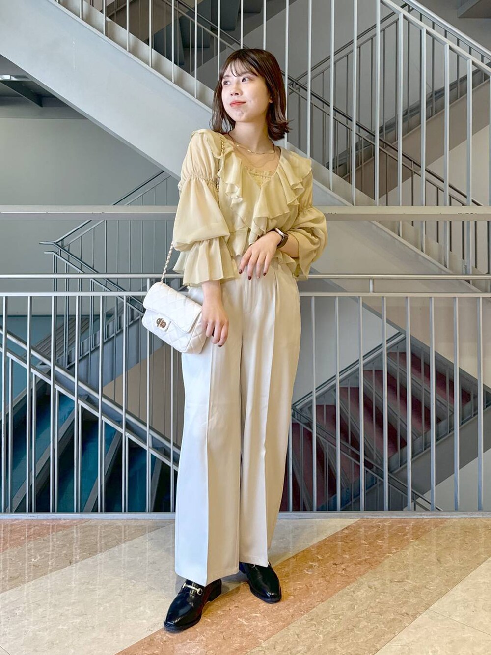 ブラック系のローファー、イエロー系のシャツ/ブラウス、ホワイト系のショルダーバッグを着用したレディースの冬コーディネートの4枚目の写真