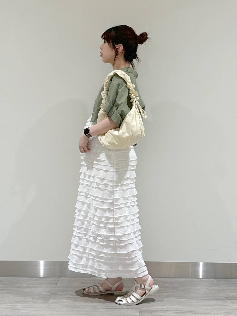 ホワイト系のショルダーバッグ、ベージュ系のキャミソール、グリーン系のミリタリージャケットを着用したレディースの夏コーディネートの3枚目の写真