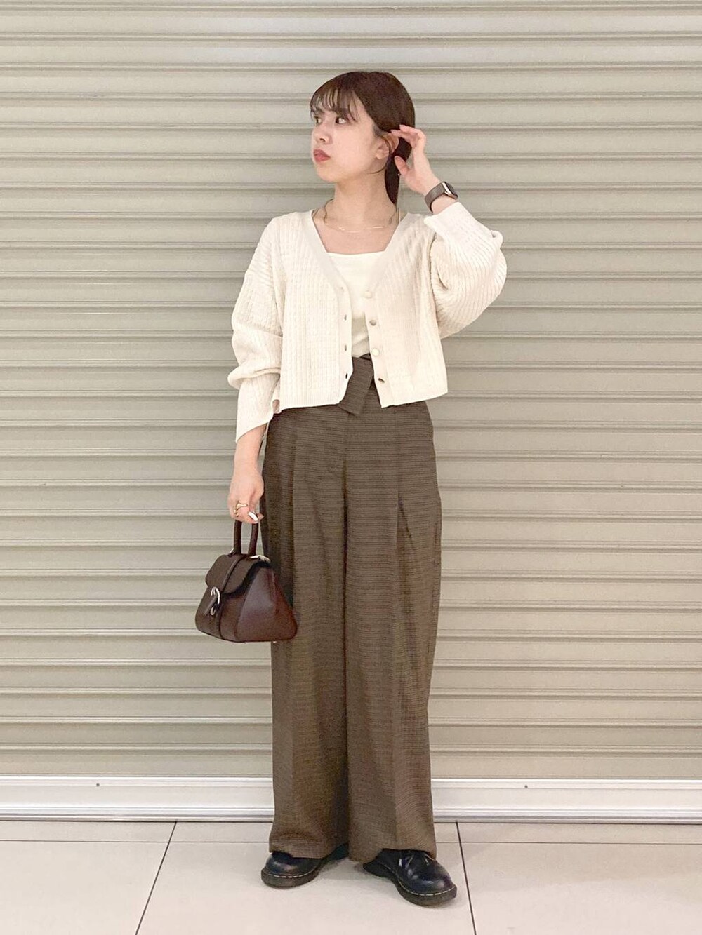 ホワイト系のタンクトップ、ブラウン系のハンドバッグ、ホワイト系のカーディガン/ボレロを着用したレディースの秋コーディネートの4枚目の写真