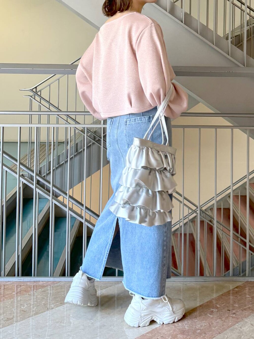 シルバー系のトートバッグ、ホワイト系のスニーカー、ブルー系のスカートを着用したレディースの冬コーディネートの2枚目の写真