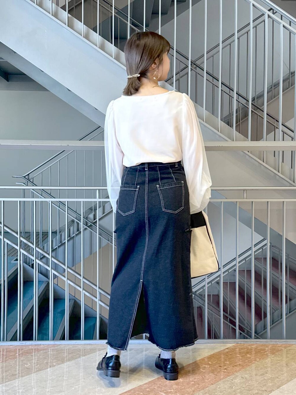 ブラック系のトートバッグ、ブラック系のローファー、ブラック系のスカートを着用したレディースの冬コーディネートの3枚目の写真