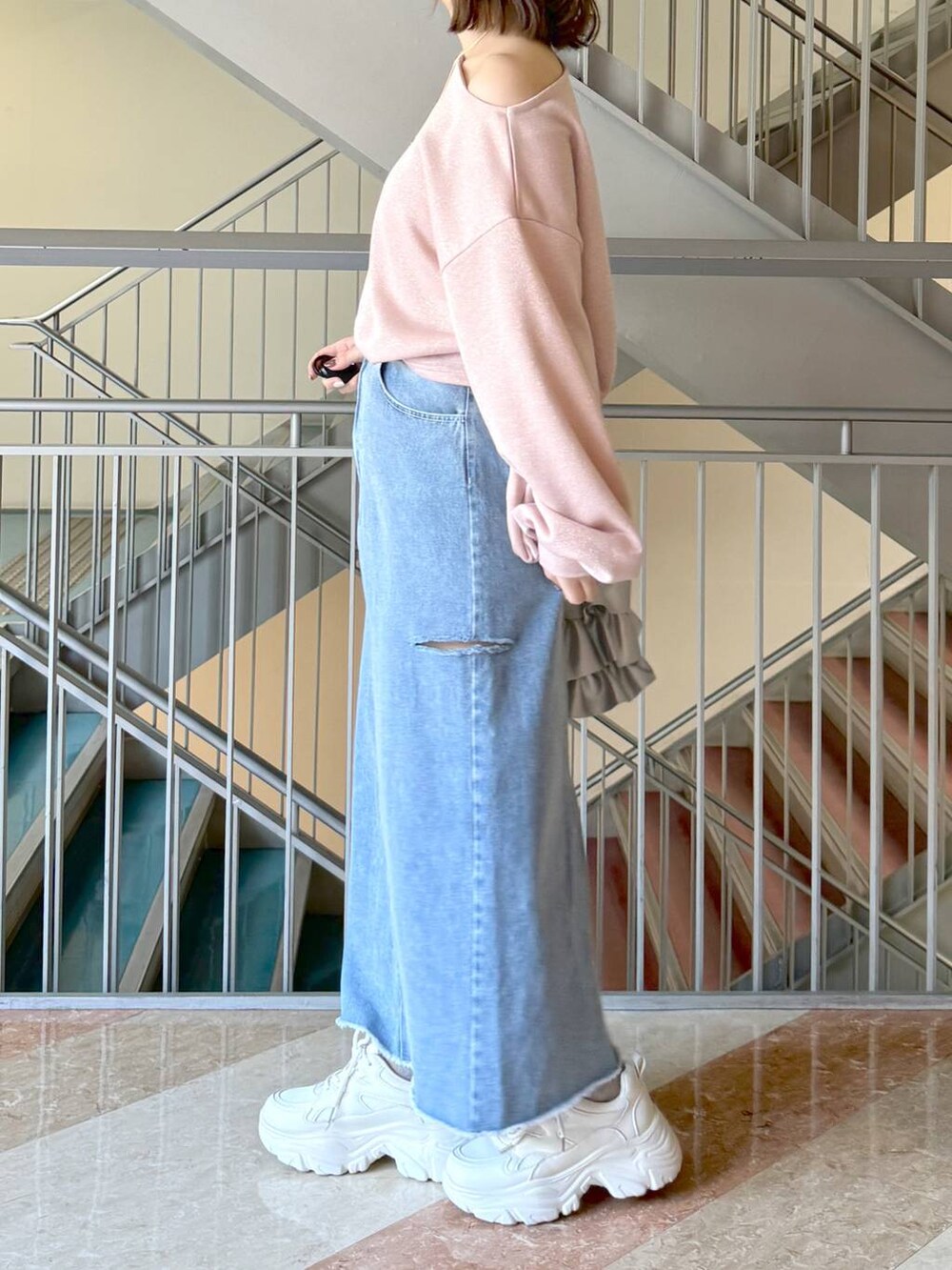 シルバー系のトートバッグ、ホワイト系のスニーカー、ブルー系のスカートを着用したレディースの冬コーディネートの3枚目の写真