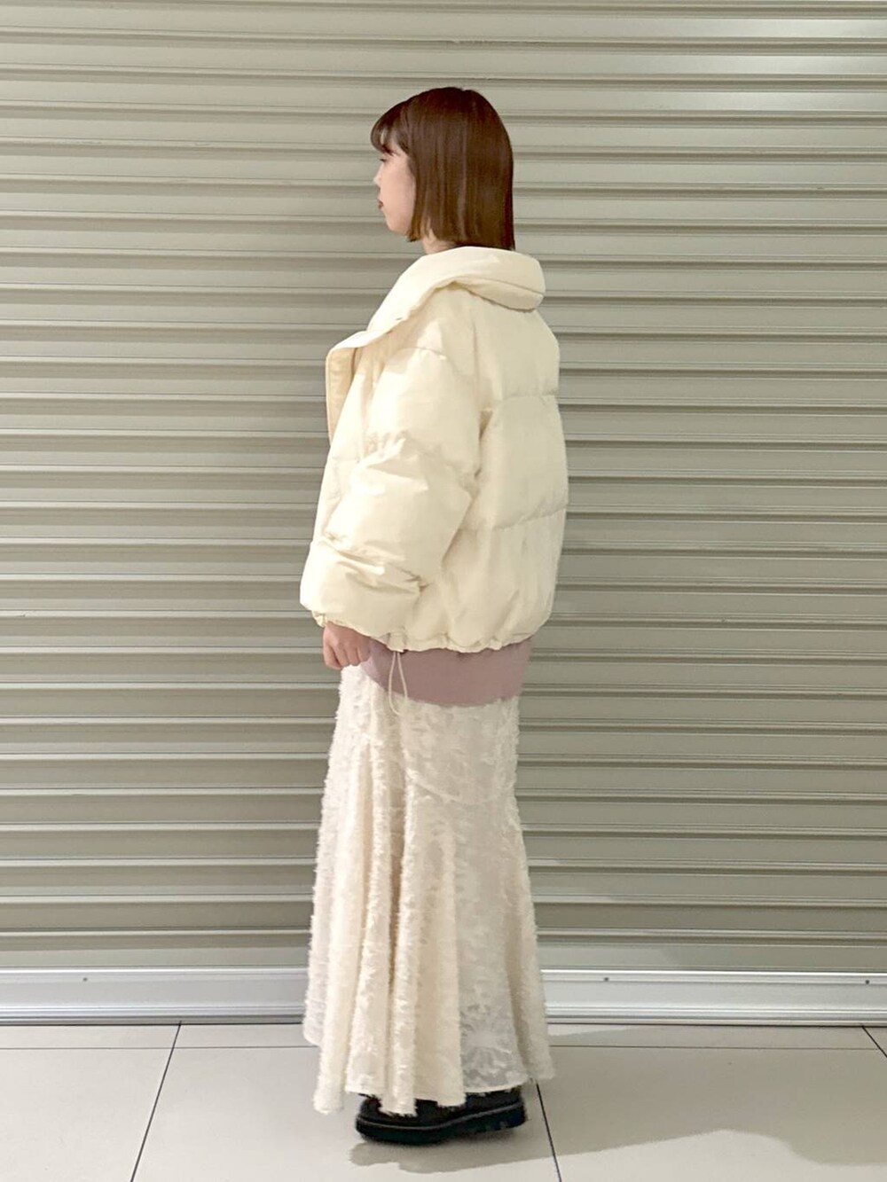 ブラック系のブーツ、ピンク系のニット/セーター、ホワイト系のトートバッグを着用したレディースの冬コーディネートの2枚目の写真