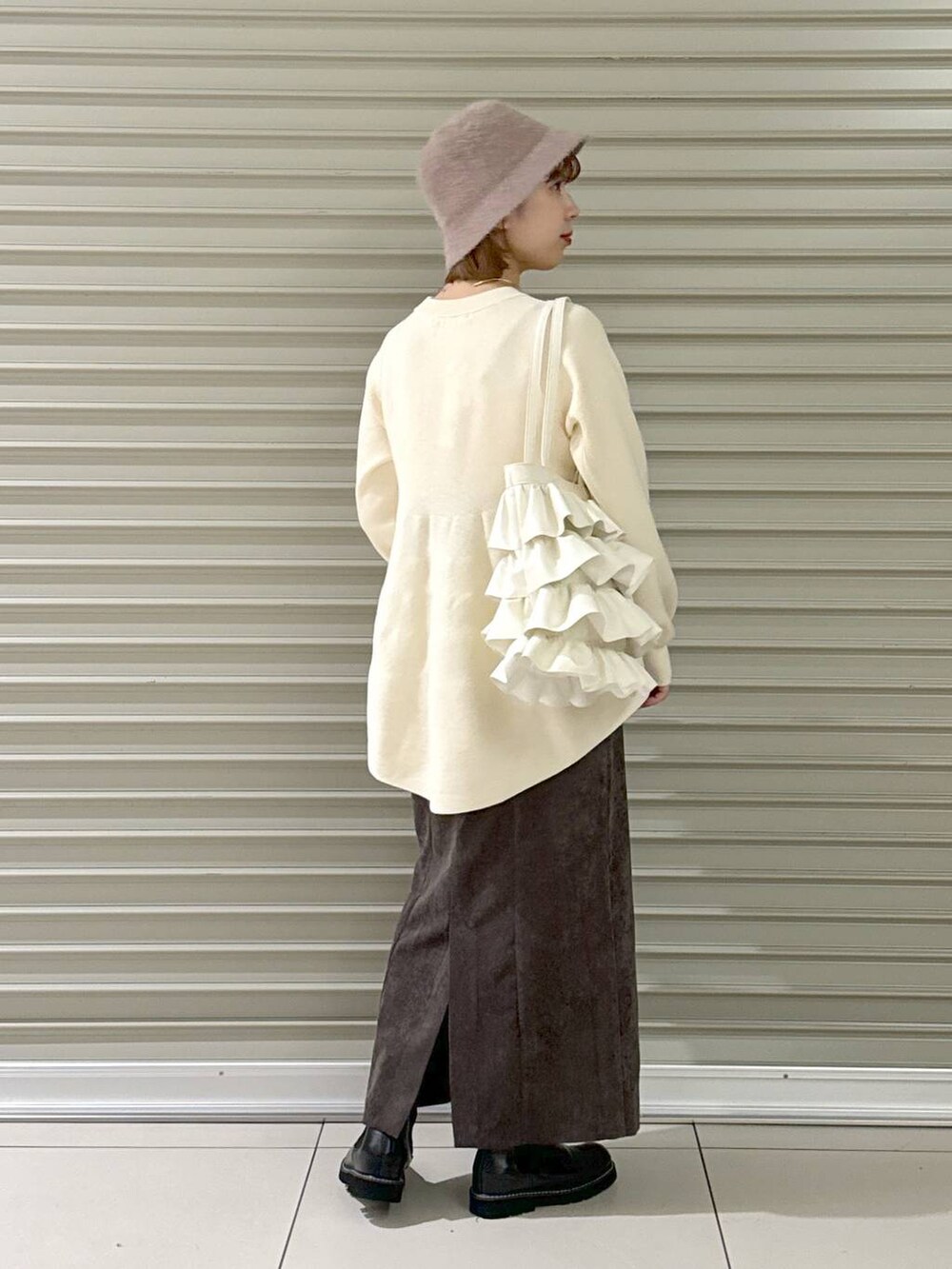 ブラウン系のスカート、ブラック系のブーツ、ホワイト系のトートバッグを着用したレディースの冬コーディネートの2枚目の写真