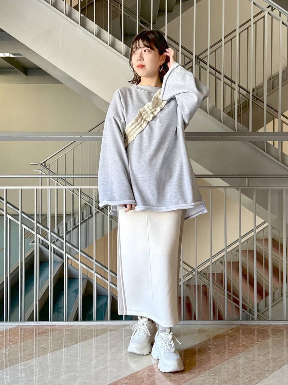 ホワイト系のスカート、グレー系のスウェット、ホワイト系のハンドバッグを着用したレディースの冬コーディネートの4枚目の写真