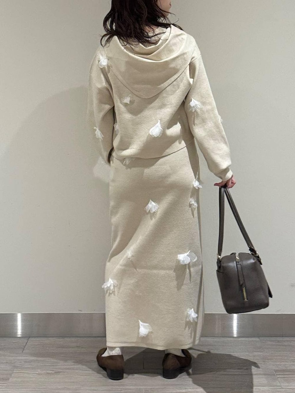 ブラウン系のハンドバッグ、ブラウン系のローファー、ホワイト系のニット/セーターを着用したレディースの冬コーディネートの5枚目の写真