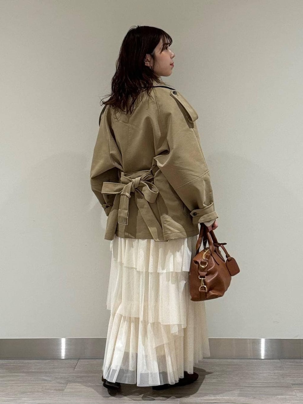 ブラウン系のボストンバッグ、ブラウン系のローファー、ホワイト系のスカートを着用したレディースの冬コーディネートの3枚目の写真