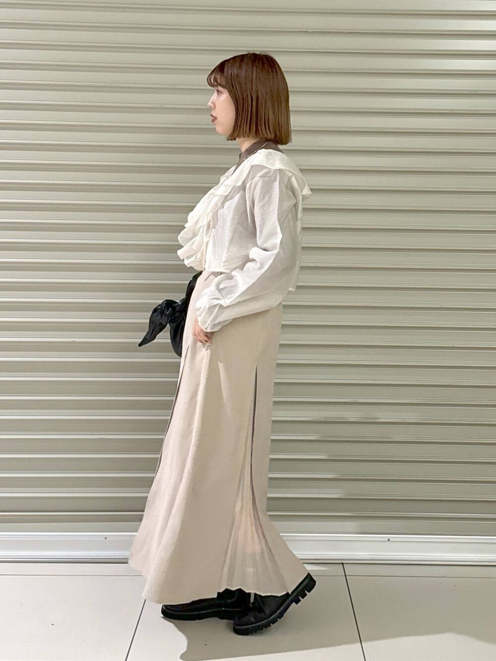 ブラック系のブーツ、ブラウン系のニット/セーター、ブラック系のハンドバッグを着用したレディースの冬コーディネートの2枚目の写真