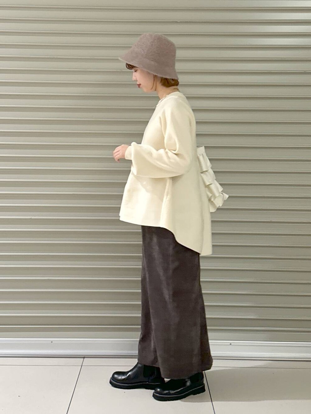 ブラウン系のスカート、ブラック系のブーツ、ホワイト系のトートバッグを着用したレディースの冬コーディネートの3枚目の写真