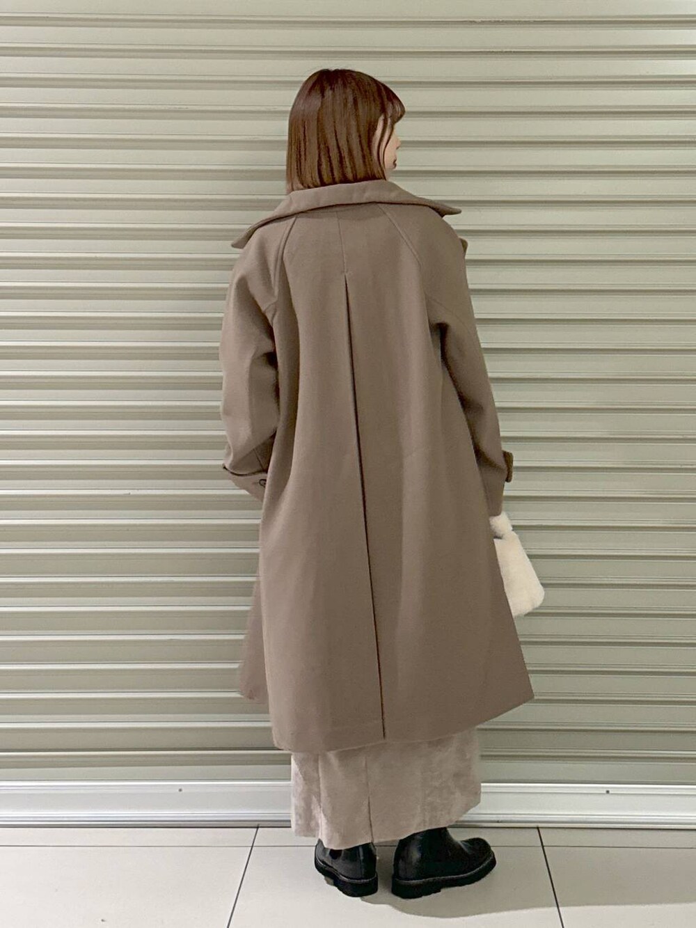 ブラウン系のスカート、ブラウン系のチェスターコート、ホワイト系のキャミソールを着用したレディースの冬コーディネートの3枚目の写真