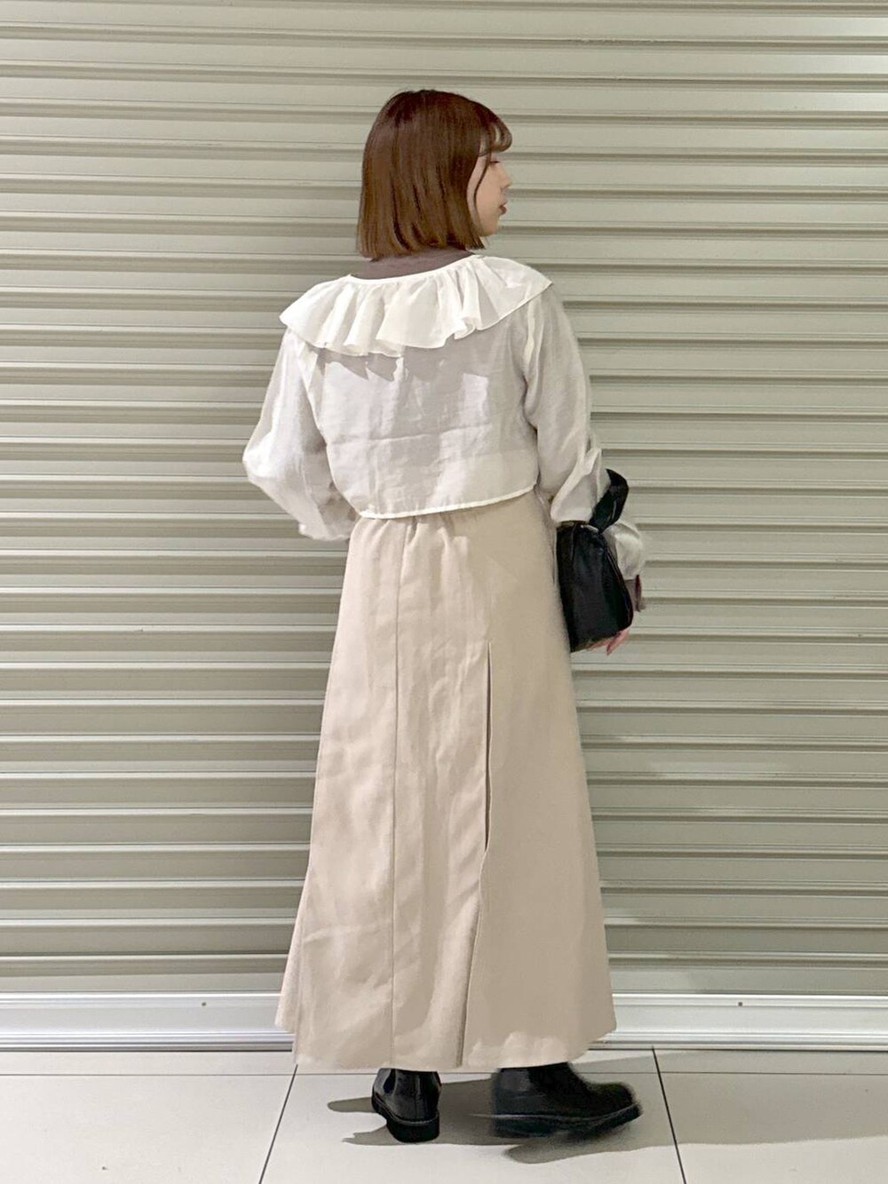 ブラック系のブーツ、ブラウン系のニット/セーター、ブラック系のハンドバッグを着用したレディースの冬コーディネートの3枚目の写真