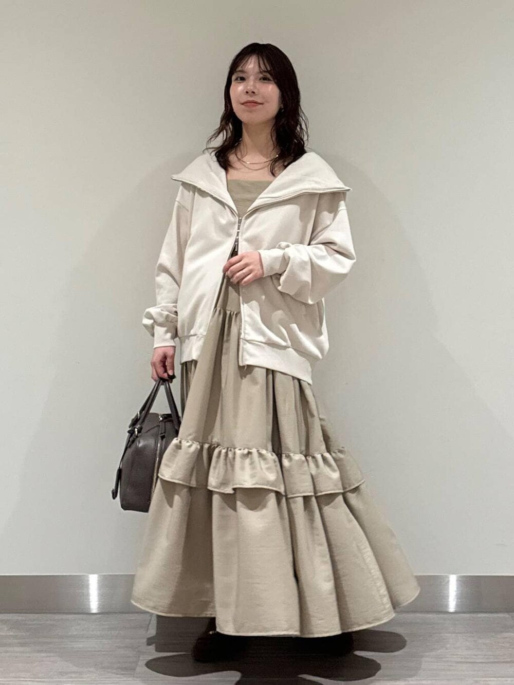 ホワイト系のキャミソール、ブラウン系のハンドバッグ、ブラウン系のローファーを着用したレディースの冬コーディネートの5枚目の写真