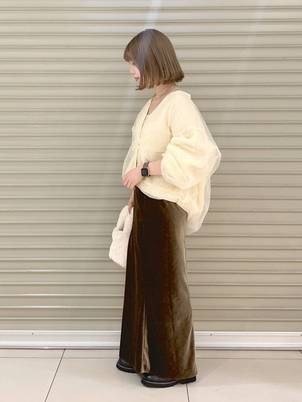 ベージュ系のキャミソール、ホワイト系のカーディガン/ボレロ、ブラウン系のスカートを着用したレディースの秋コーディネートの2枚目の写真