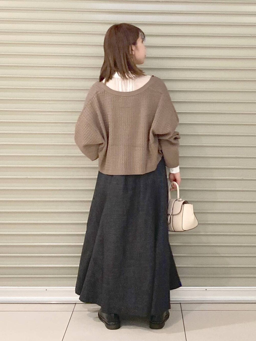 ホワイト系のハンドバッグ、ブラウン系のカーディガン/ボレロ、グレー系のワンピースを着用したレディースの秋コーディネートの4枚目の写真