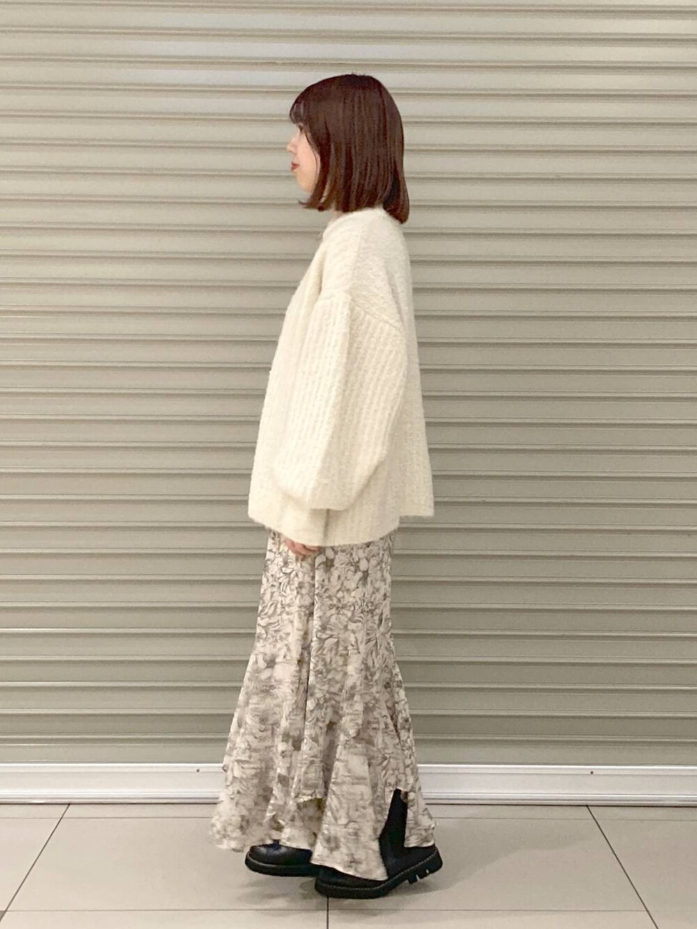 ブラック系のブーツ、ホワイト系のニット/セーター、ホワイト系のスカートを着用したレディースの冬コーディネートの2枚目の写真