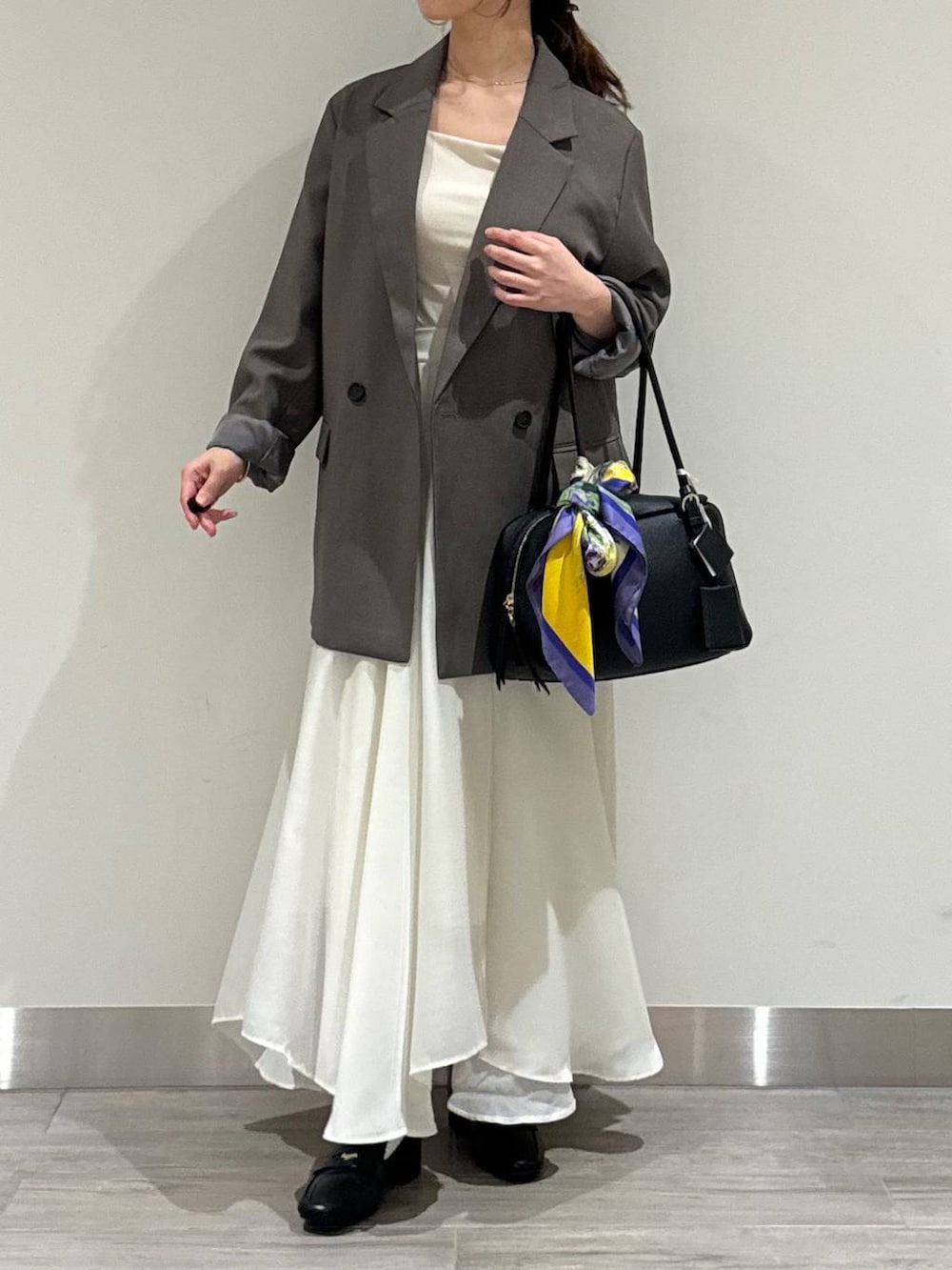 ブラック系のハンドバッグ、ベージュ系のテーラードジャケット、ホワイト系のスカートを着用したレディースの秋コーディネートの3枚目の写真