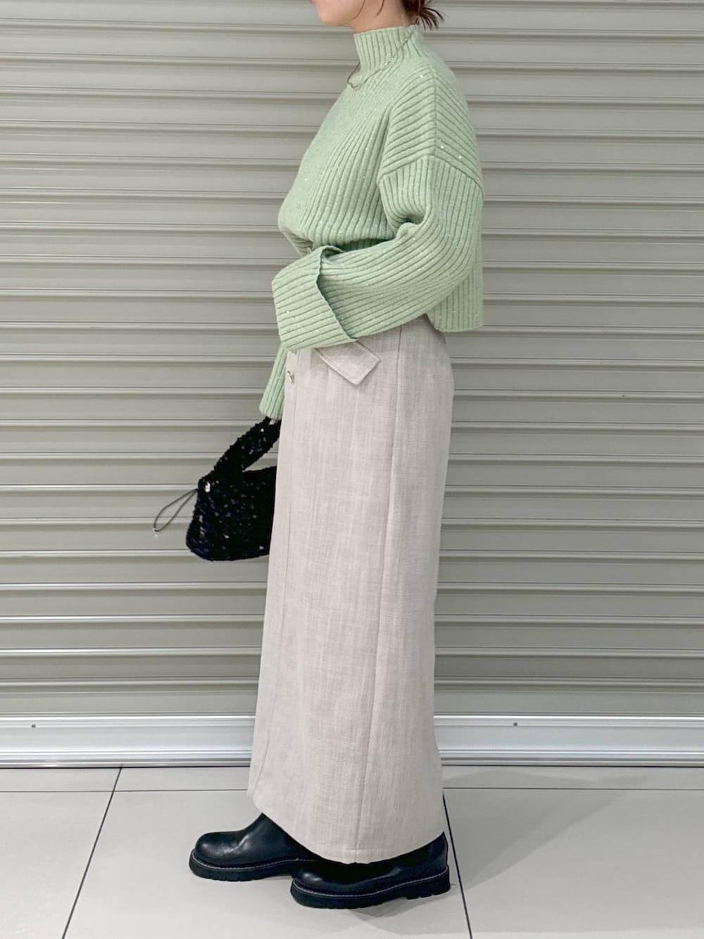 ブラック系のブーツ、ホワイト系のスカート、ブラック系のハンドバッグを着用したレディースの冬コーディネートの4枚目の写真