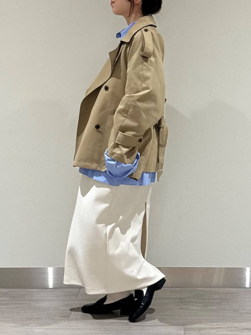 ブラック系のローファー、ベージュ系のトレンチコート、グレー系のニット/セーターを着用したレディースの春コーディネートの2枚目の写真