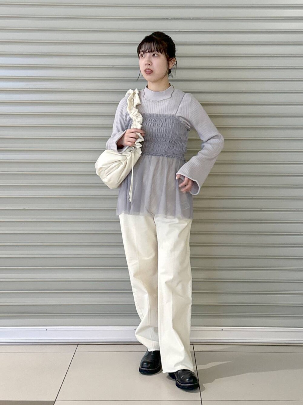 ホワイト系のデニムパンツ、ホワイト系のハンドバッグ、ブラック系のブーツを着用したレディースの冬コーディネートの2枚目の写真