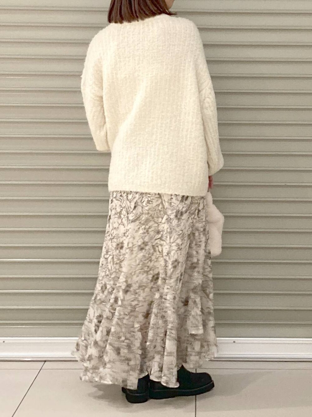 ブラック系のブーツ、ホワイト系のニット/セーター、ホワイト系のスカートを着用したレディースの冬コーディネートの3枚目の写真